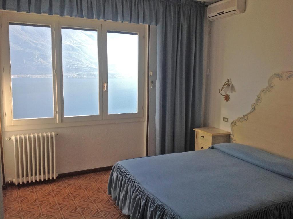 a bedroom with a bed and a large window at Hotel Villa Margherita in Limone sul Garda