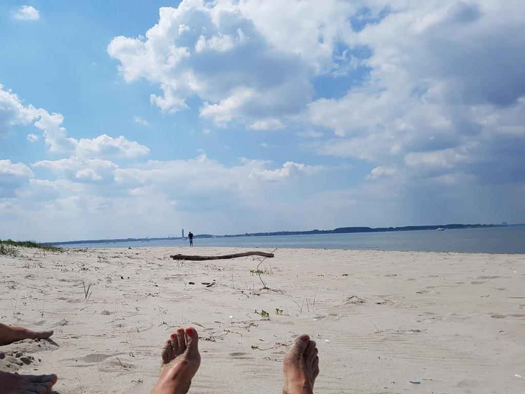 eine Person, die am Strand mit ihren Füßen im Sand sitzt in der Unterkunft Seesternchen in Groß Schwansee