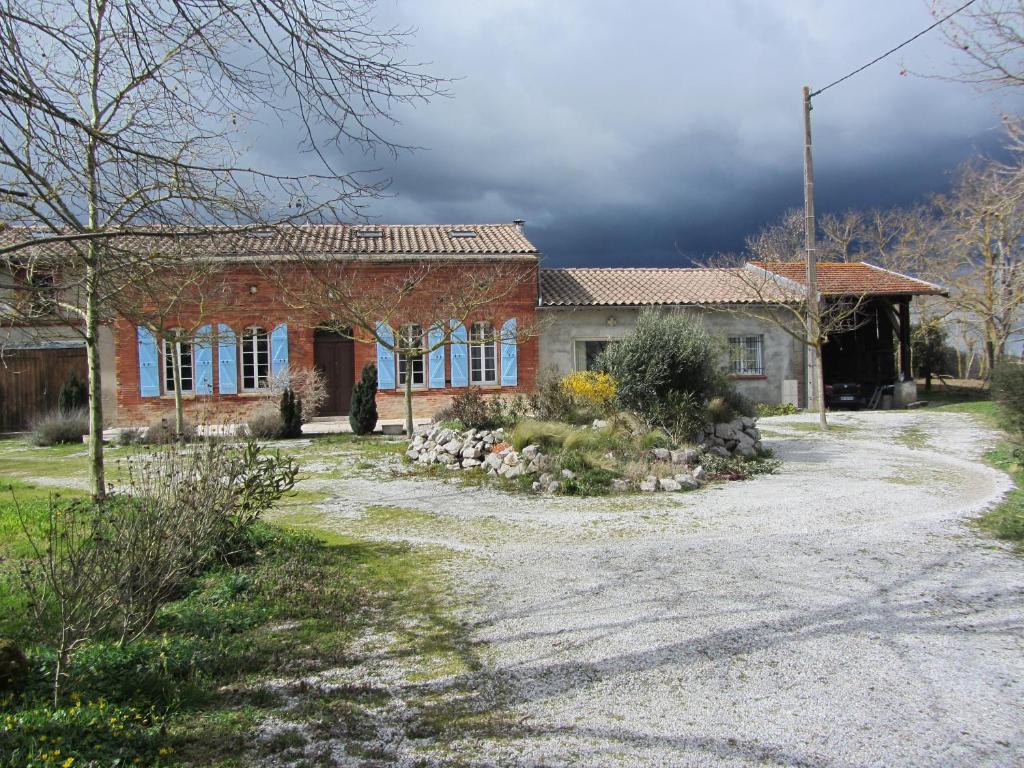 a brick house with a gravel driveway in front of it at Le Piquet in Fonsorbes