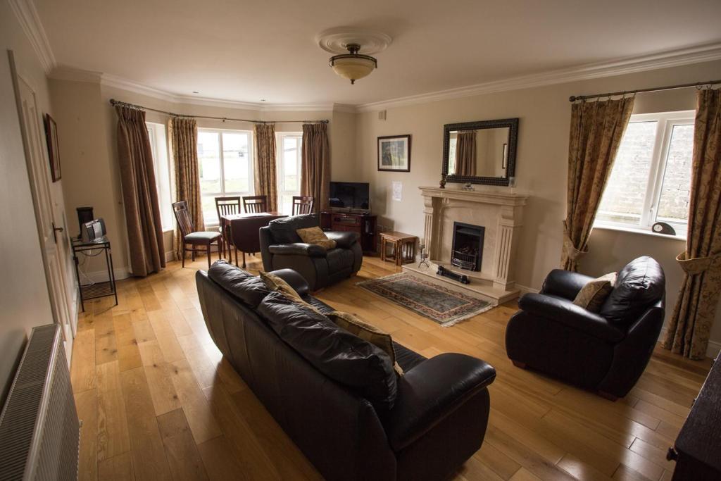 a living room with leather furniture and a fireplace at Teach Bhalor in Falcarragh