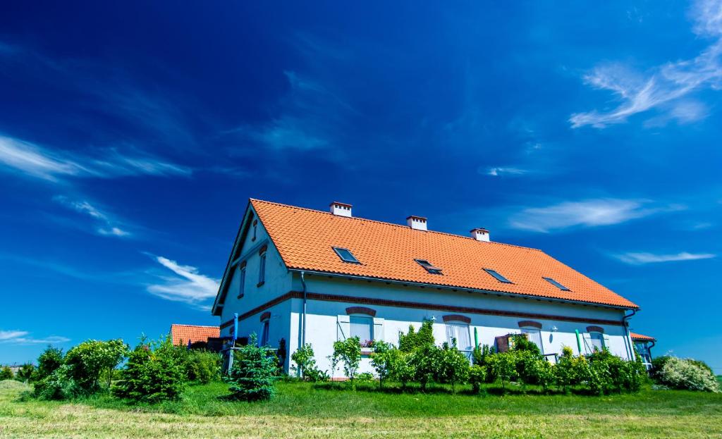 a house with an orange roof on a green field at Fajne Miejsce in Jeziorany