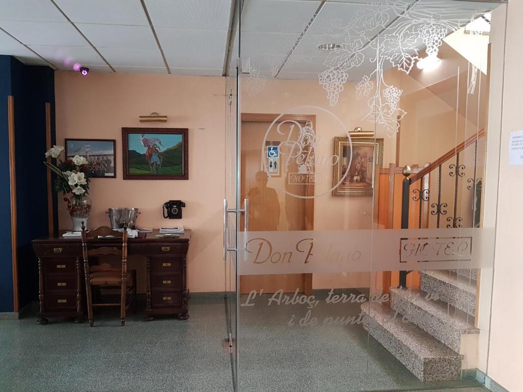 - une porte en verre dans une chambre avec un bureau et des escaliers dans l'établissement Hotel Don Pelayo, à Arbós