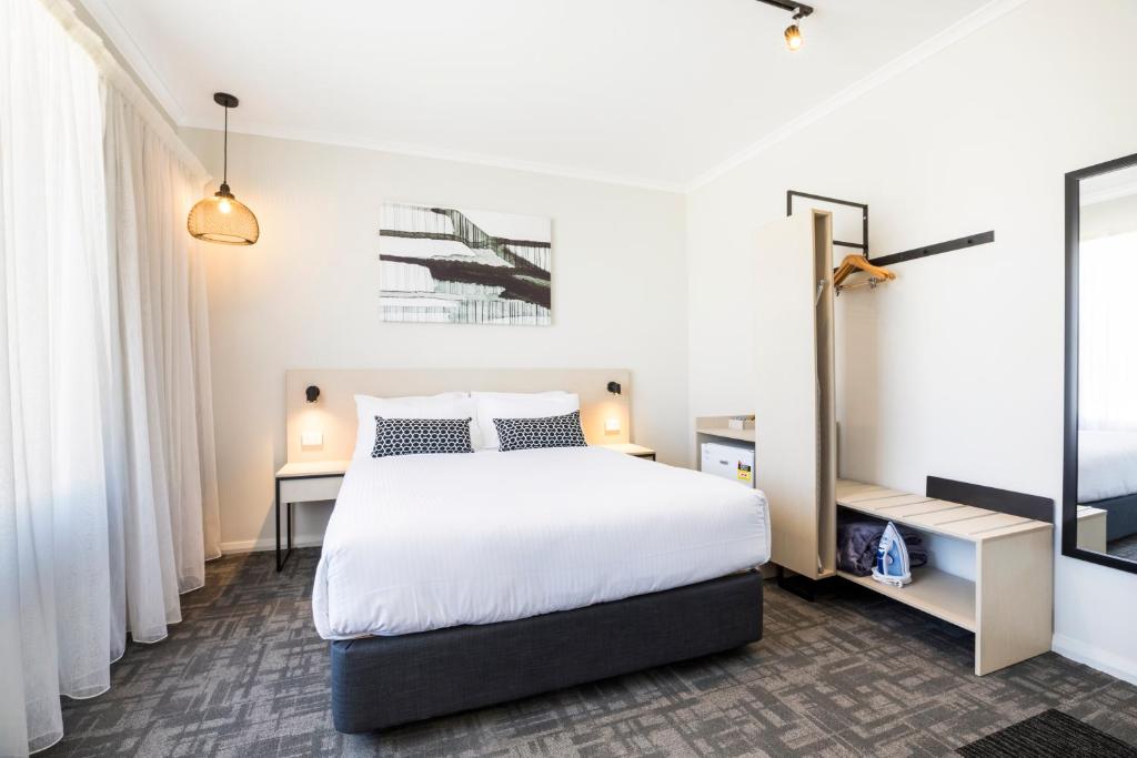 a bedroom with a large white bed and a mirror at Nightcap at Finsbury Hotel in Adelaide
