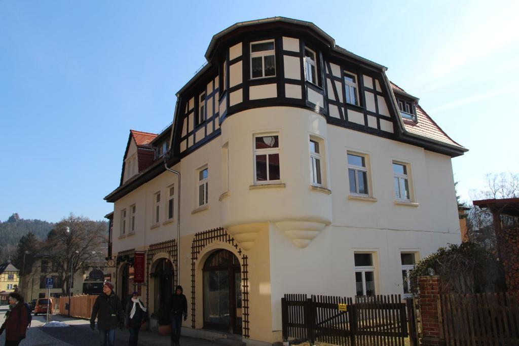 a white and black building with people walking around it at Ferienwohnung Detlef Pascher in Oybin