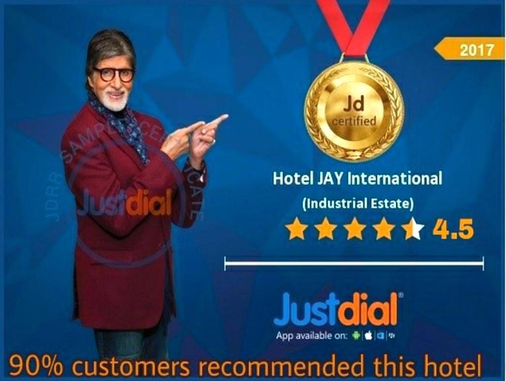 Ein Mann steht neben einer Medaille in der Unterkunft Hotel Jay International in Vapi
