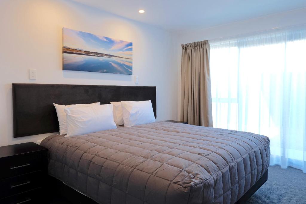 a bedroom with a bed and a large window at Stopforths Motel in Hokitika