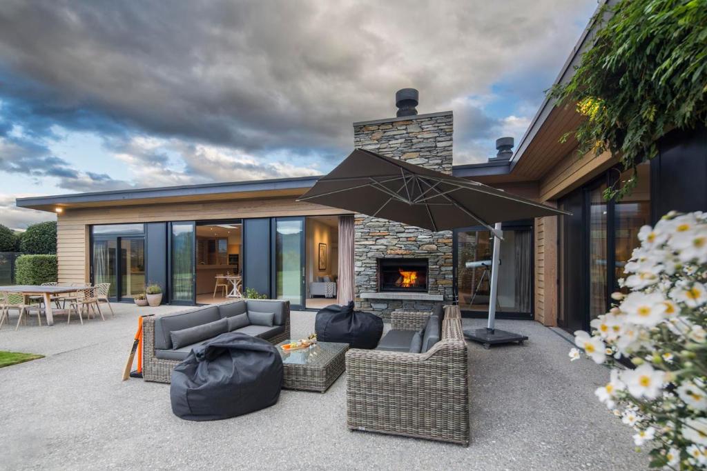 a patio with a couch and an umbrella and a fireplace at Alpine Retreat in Queenstown
