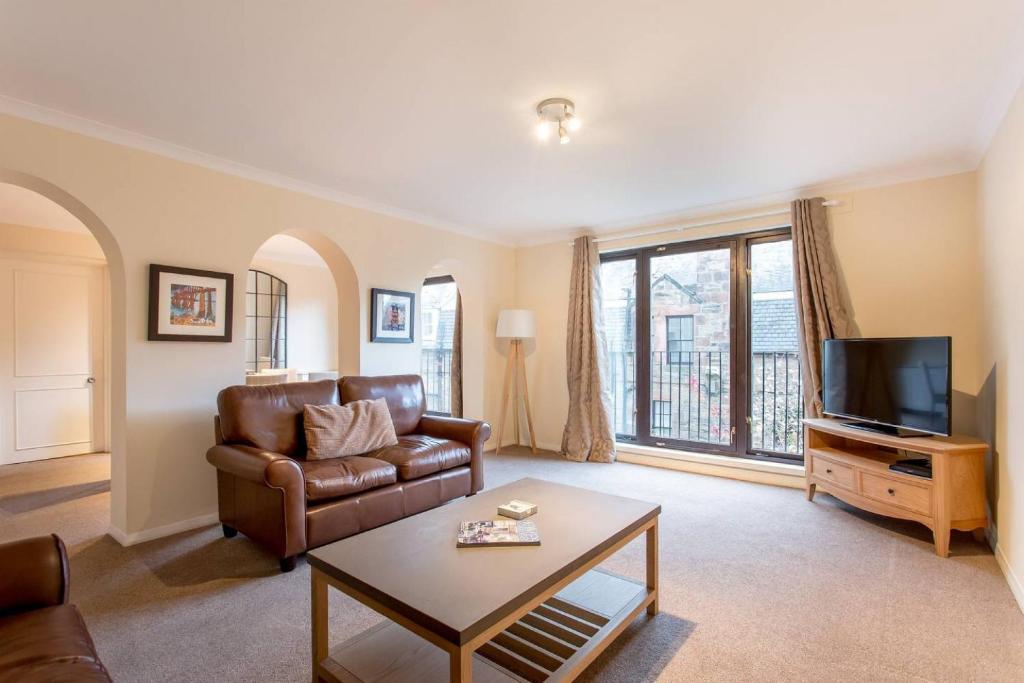 a living room with a leather couch and a television at ALTIDO Historic City Centre Apt with Free Secure Parking - No SUVs in Edinburgh