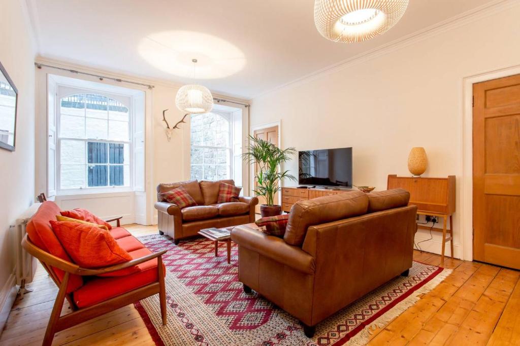 een woonkamer met een bank en stoelen en een tv bij JOIVY Spacious 2 Bed Apt in Ideal City Centre Location in Edinburgh