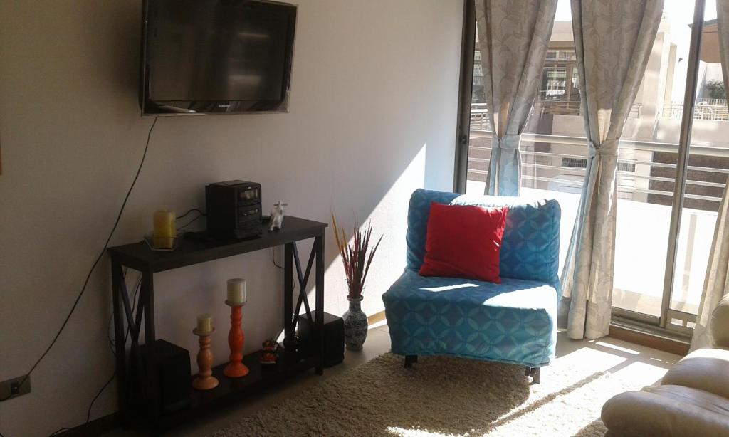 sala de estar con silla y TV en Departamento Atlántico 4030, en Viña del Mar
