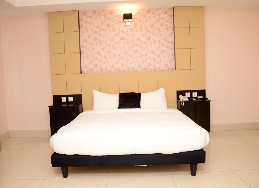 a bedroom with a large white bed and a painting on the wall at BWC Hotel in Lagos