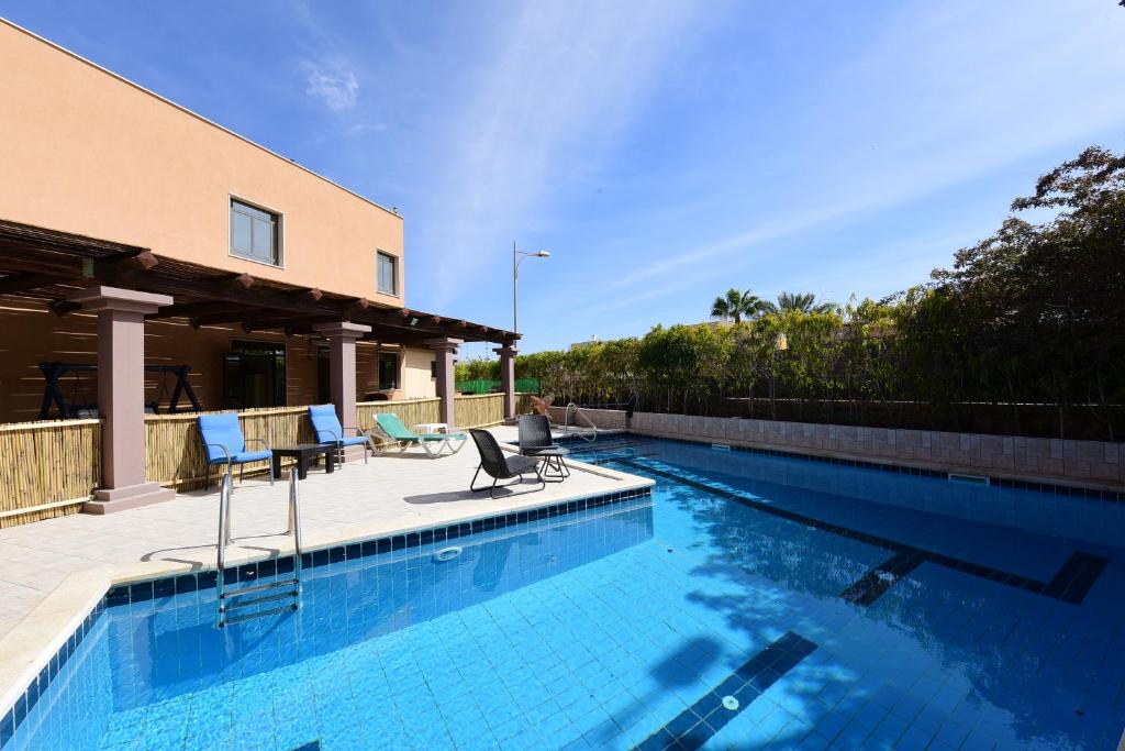 a swimming pool with chairs and a house at Flintstone Guest House in Eilat