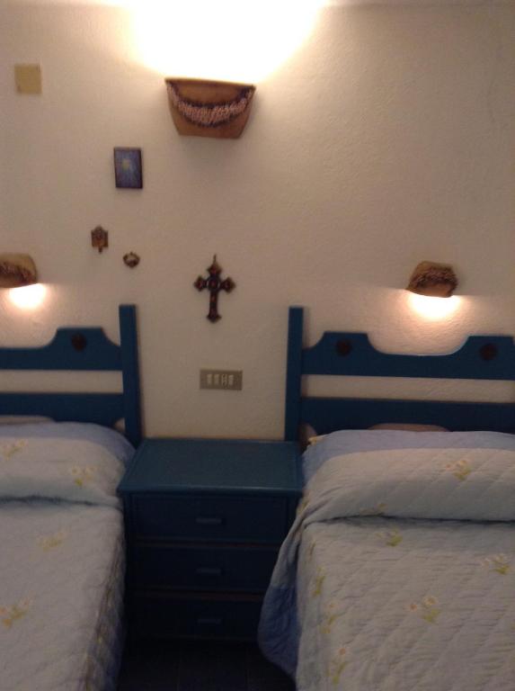 a bedroom with two beds and a cross on the wall at Residence Vulcano Cottage in Vulcano