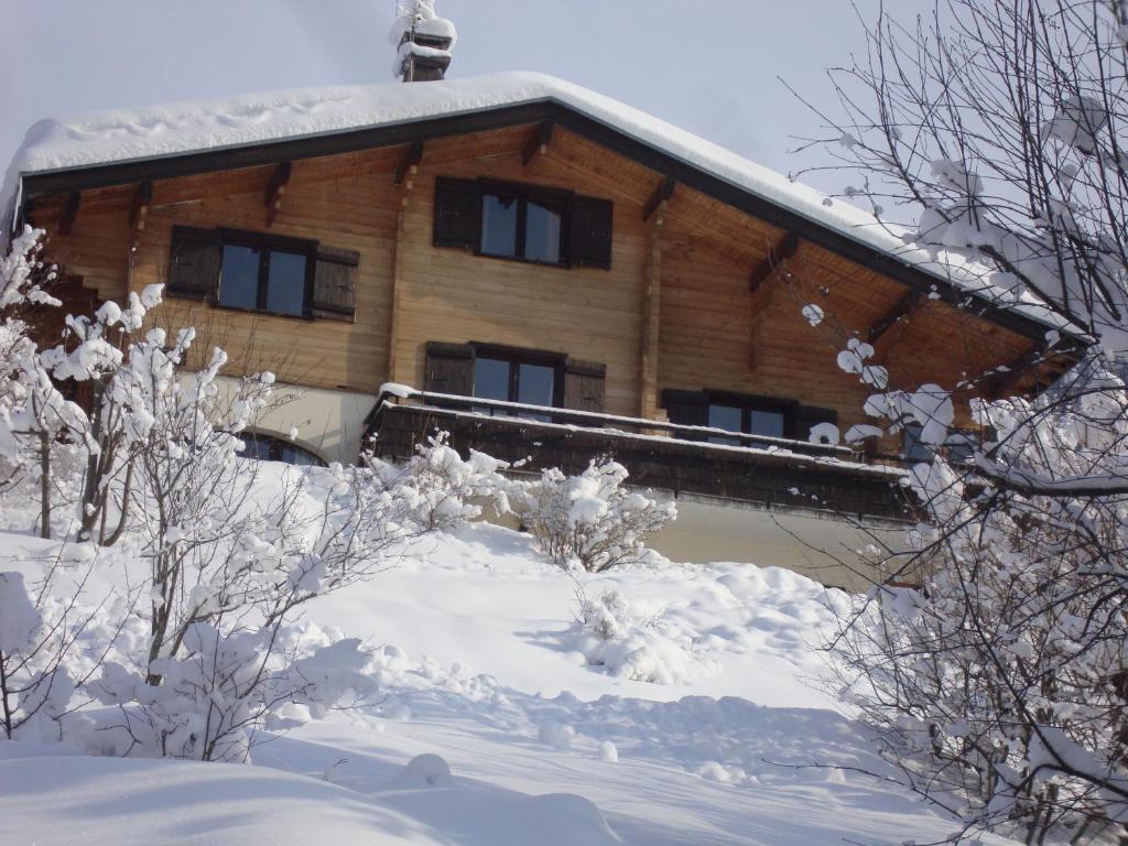una cabaña de madera con nieve en el suelo frente a ella en Chambre d'Hôtes La Trace en La Clusaz
