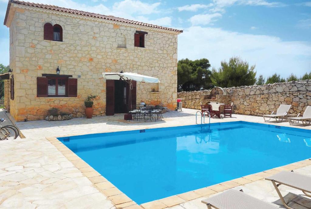 a large swimming pool in front of a stone house at Ira Agios Leon Zakynthos in Agios Leon