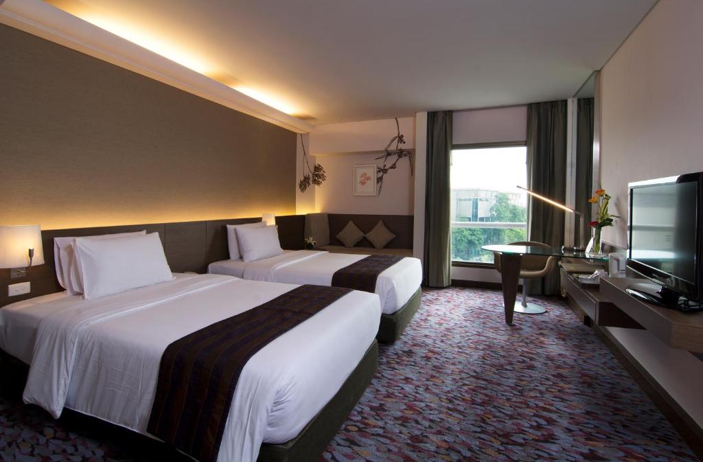 A twin room with a window-side sitting table and television opposite the beds.