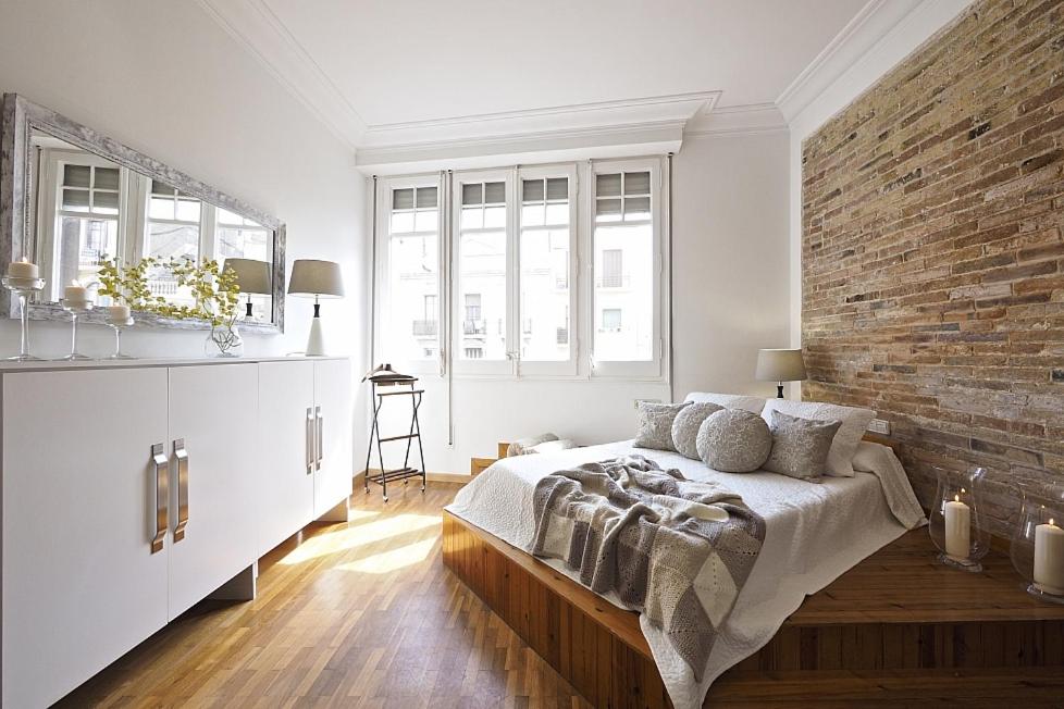 a bedroom with a large bed with a brick wall at Ático para 10 en Plaza España 075 in Barcelona