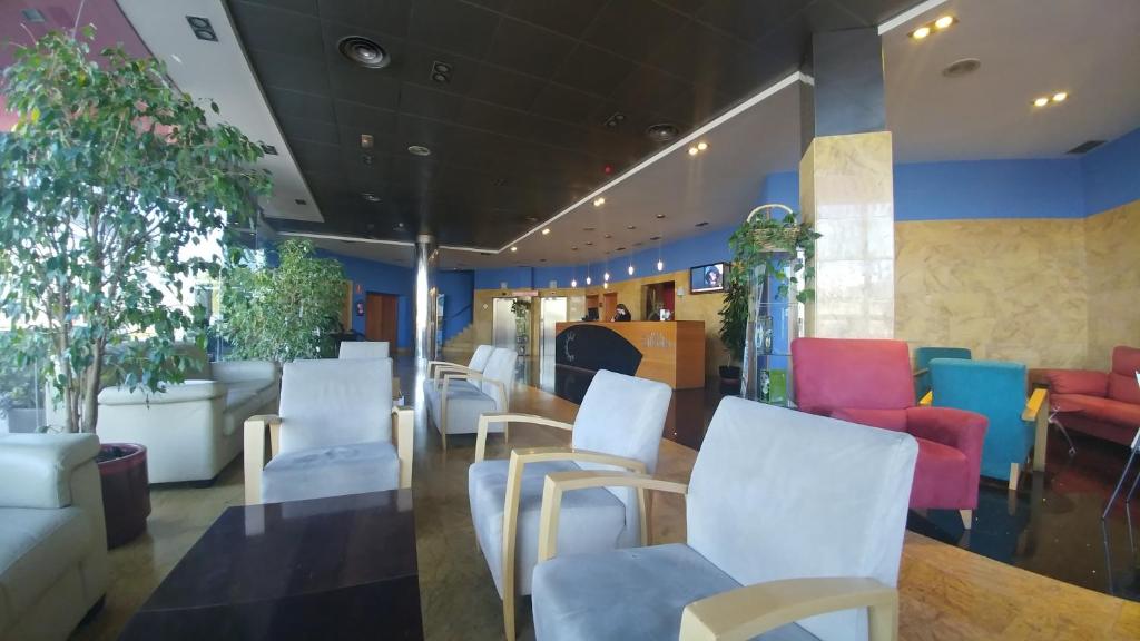 un restaurante con sillas blancas y sillas coloridas en Hotel Silvota, en Lugo de Llanera