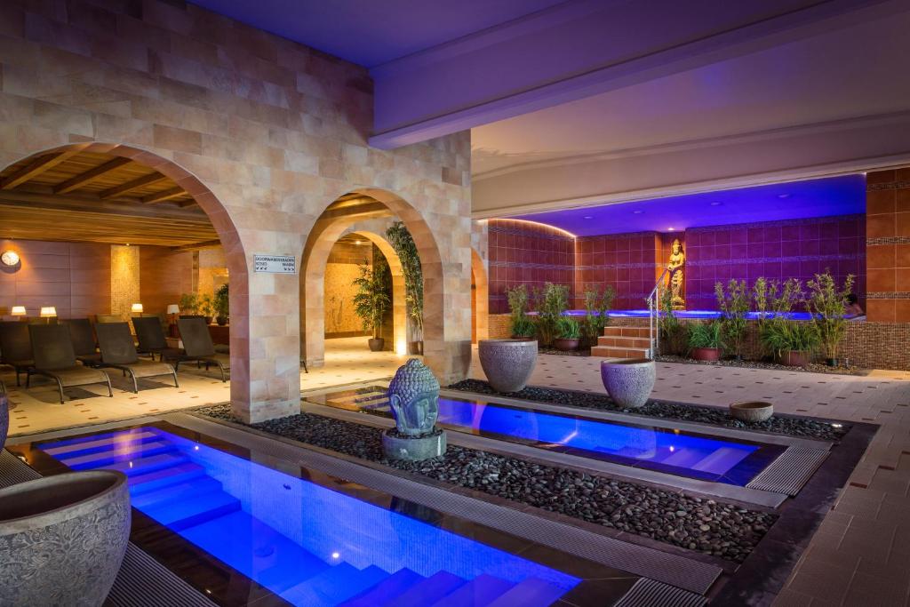 a swimming pool in a house with blue lighting at Thermen Londerzeel Hotel in Londerzeel