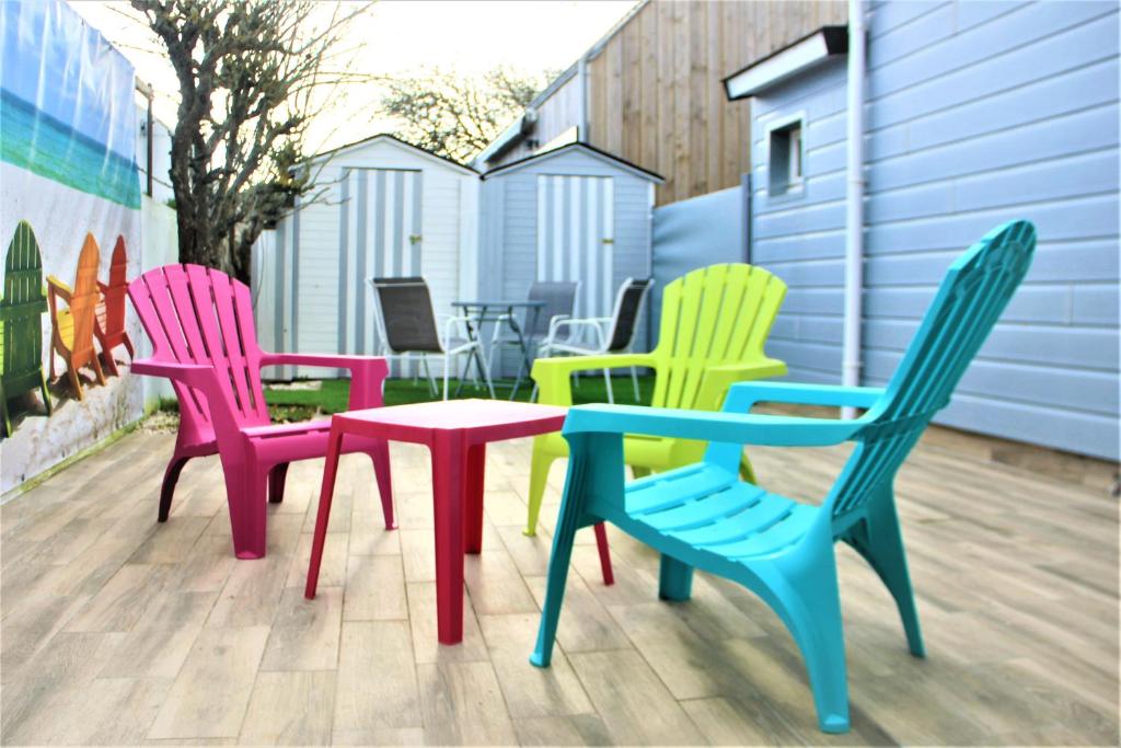 vier kleurrijke stoelen en een tafel op een patio bij La cabine de plage in Batz-sur-Mer