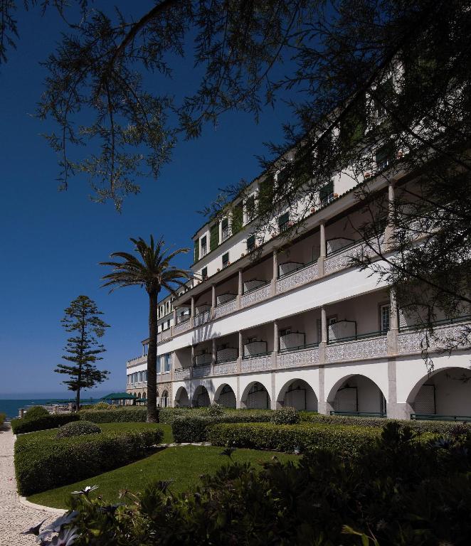 a building with a palm tree in front of it at Vila Gale Ericeira in Ericeira