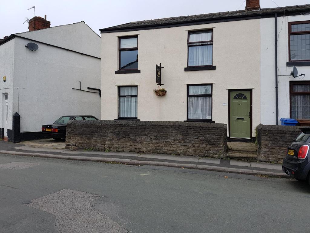 a white house with a green door on a street at Overnight Stays Stockport in Stockport