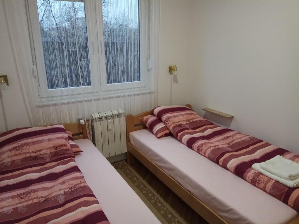 zwei Betten in einem Zimmer mit zwei Fenstern in der Unterkunft Apartman Ana in Subotica