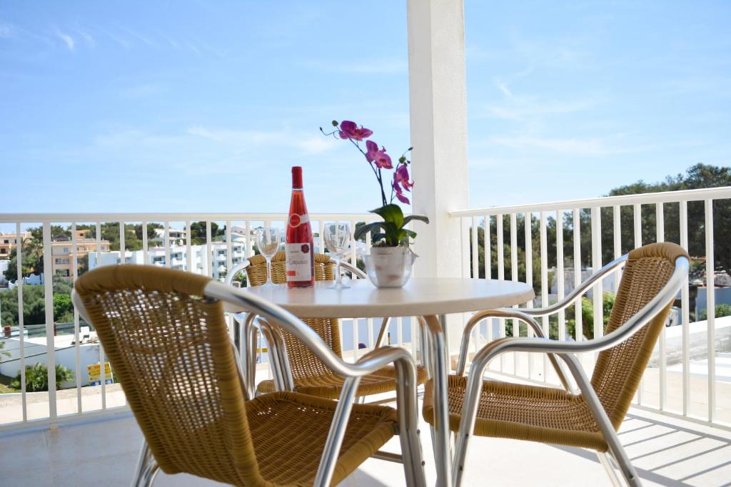 a table with two chairs and a bottle of wine on a balcony at Apartamentos Ferrera Pins in Cala Ferrera