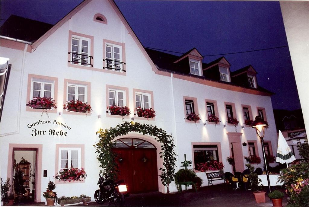 ein weißes Gebäude mit einem Bogen davor in der Unterkunft Gasthaus Zur Rebe in Mehring