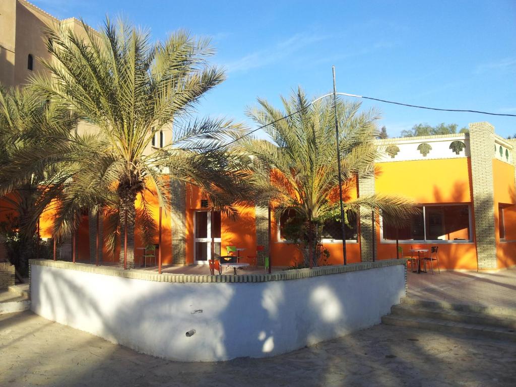 a building with palm trees in front of it at Résidence El Arich in Tozeur