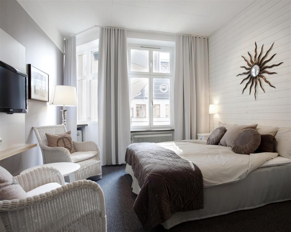 a bedroom with a large bed and two chairs at Hotel Örebro in Örebro