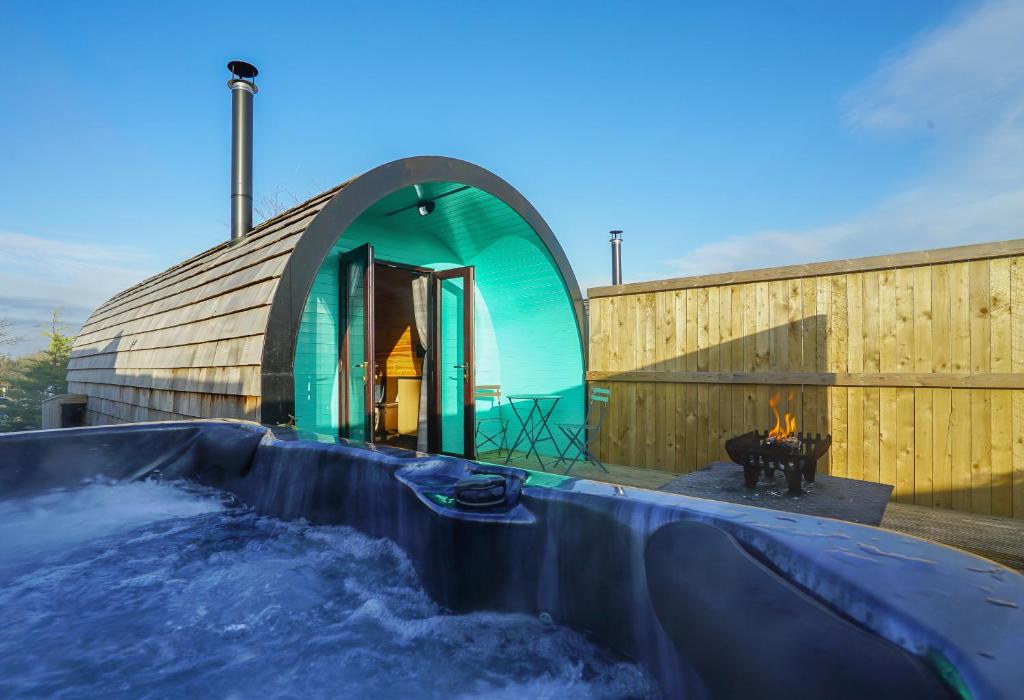 a building with a pool of water and a fireplace at Deluxe Glamping Pod with Hot Tub in Frodsham