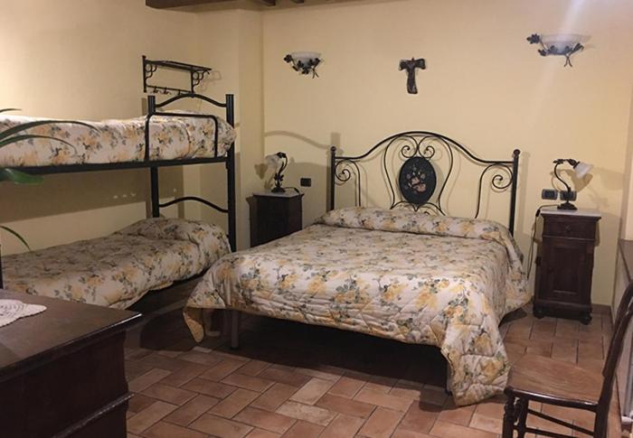 a bedroom with two beds and a cross on the wall at Il renaiolo in Spello