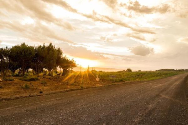 an empty road with the sun setting in the distance at Volmoed Cottage in Oudtshoorn