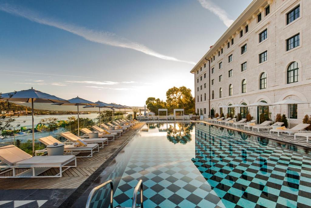 ein Hotelpool mit Stühlen und Sonnenschirmen neben einem Gebäude in der Unterkunft Hotel Brown Beach House & Spa in Trogir