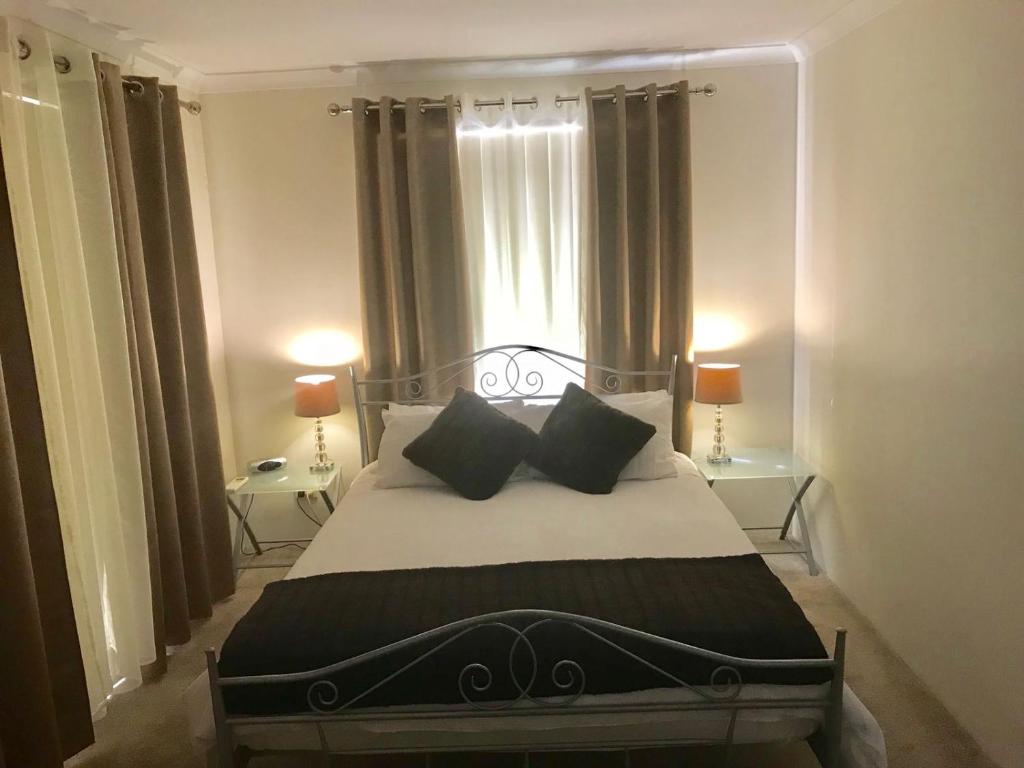 - une chambre avec un grand lit et 2 oreillers noirs dans l'établissement Joondalup Apartment, à Perth