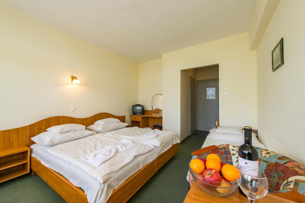 um quarto de hotel com duas camas e uma tigela de fruta numa mesa em Hotel Nostra em Siófok