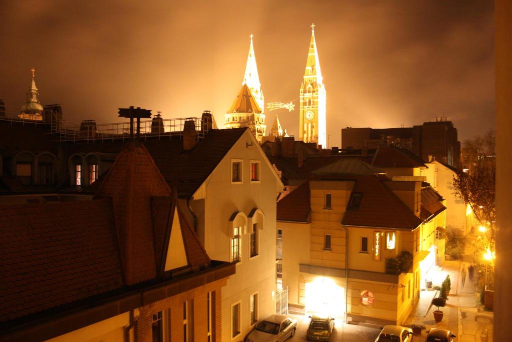 a view of a city at night with a clock tower at Dóm Hotel in Szeged