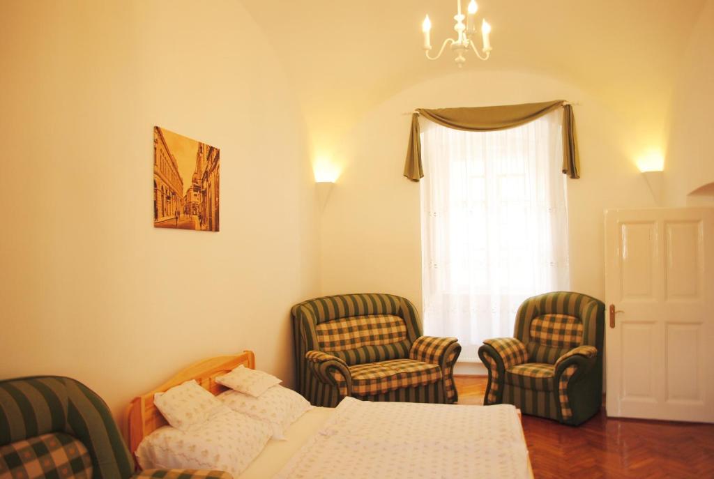 ein Wohnzimmer mit Stühlen, einem Bett und einem Fenster in der Unterkunft Dobó Téri Apartman in Eger