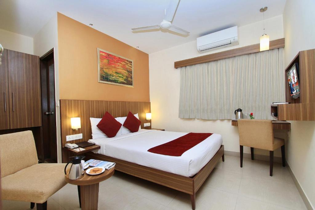 a hotel room with a bed and a desk and a chair at La Sara Comforts in Bangalore