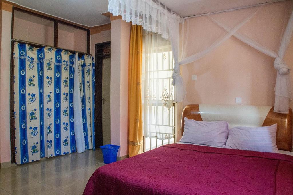 a bedroom with a pink bed and a window at Royal Crane Resort in Arua