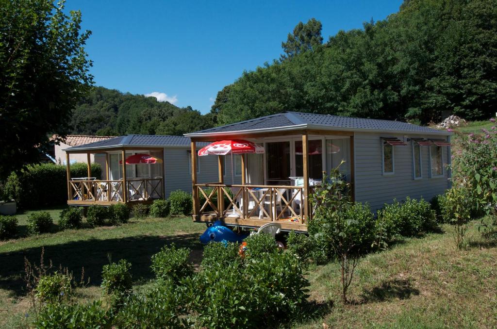 een tiny house met een veranda en een paraplu bij camping bonneval in Jaujac