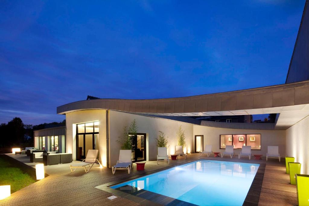 une villa avec une piscine la nuit dans l'établissement L'Aubinière Hôtel Restaurant & Spa, à Saint-Ouen-les-Vignes