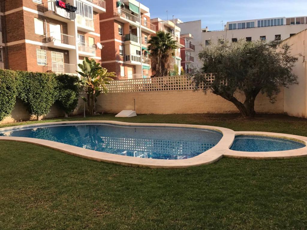 ein Pool im Gras vor einem Gebäude in der Unterkunft Piscina y playa a 2 kilómetros Alojamiento grande para familias in San Juan de Alicante