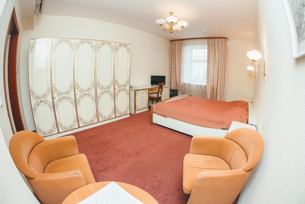 a hotel room with a bed and two chairs at Aigul Hotel in Ufa