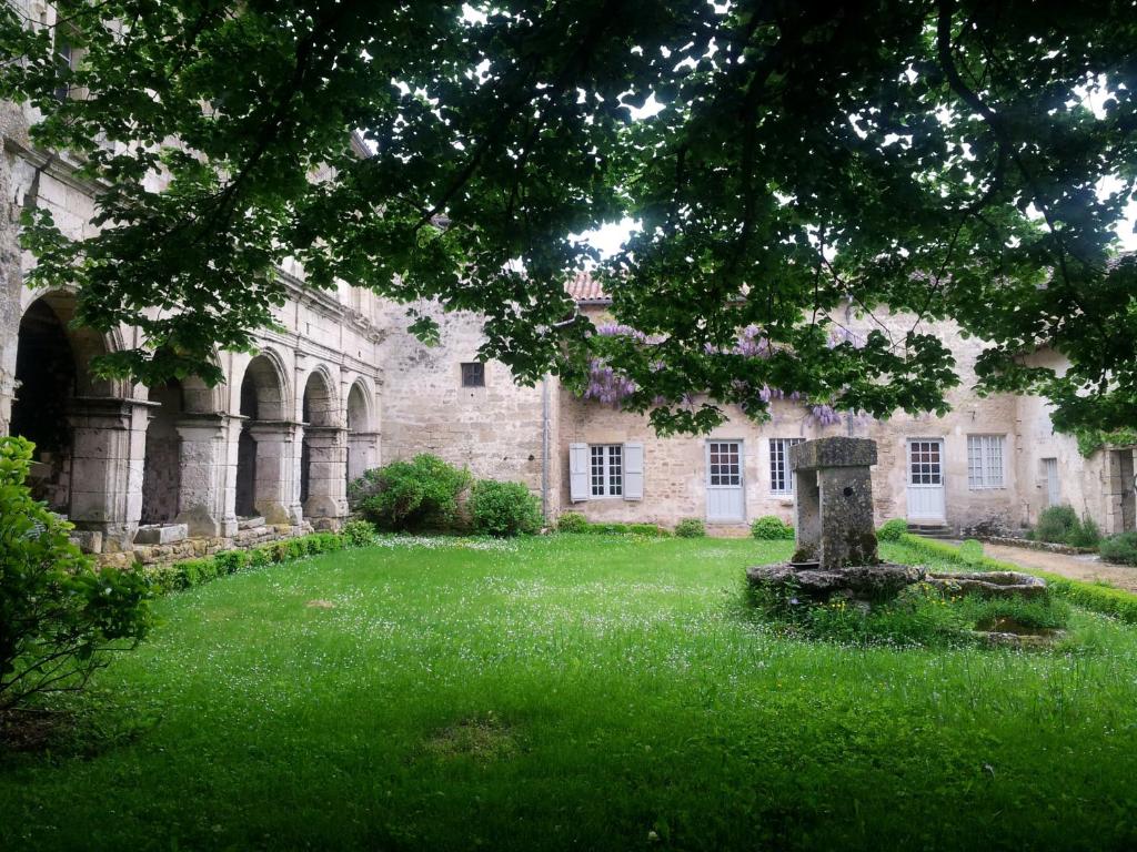 - un vieux bâtiment en pierre avec une tombe dans la cour dans l'établissement Le prieuré Saint Barthélémy, à Azay-le-Brûlé