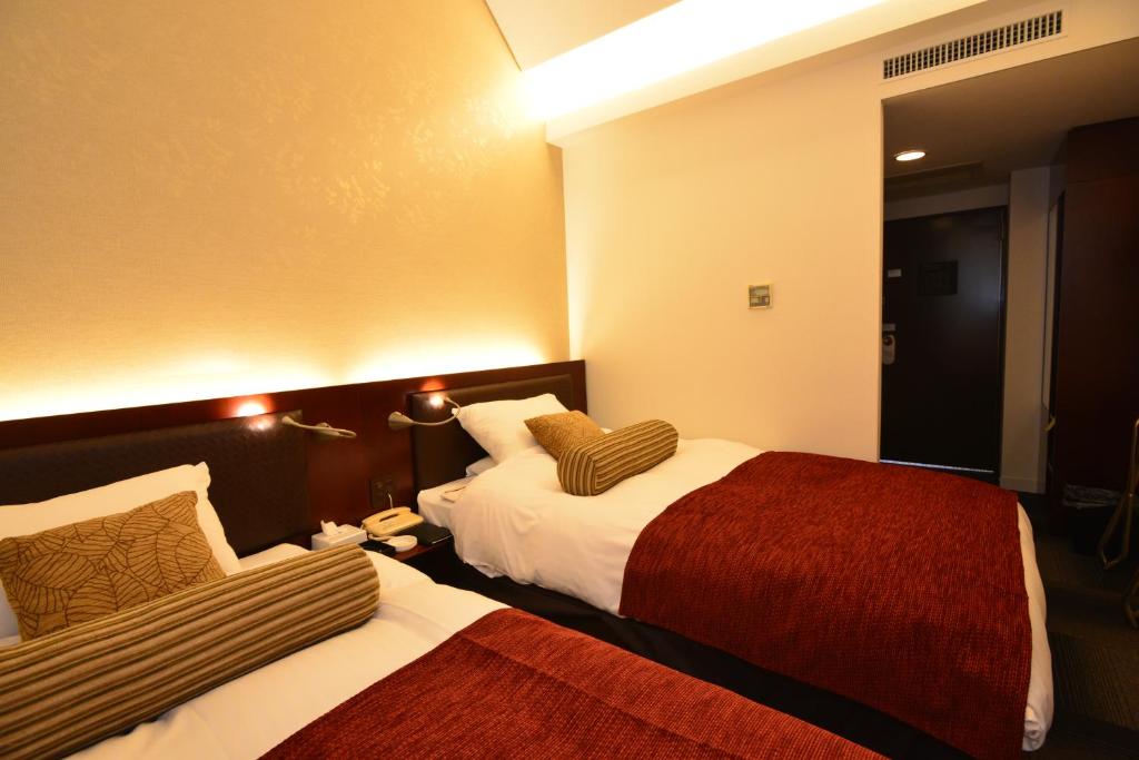 una camera d'albergo con due letti e uno specchio di Yamato Kashihara City Hotel a Kashihara
