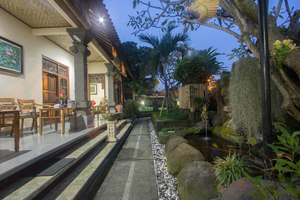 une maison avec un jardin agrémenté de rochers et d'un étang dans l'établissement Masna House, à Ubud