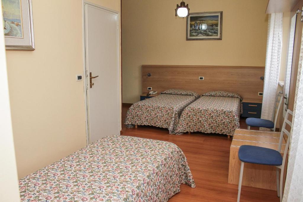 a bedroom with two beds and a table and a chair at Al Ponte della Vittoria in Belluno