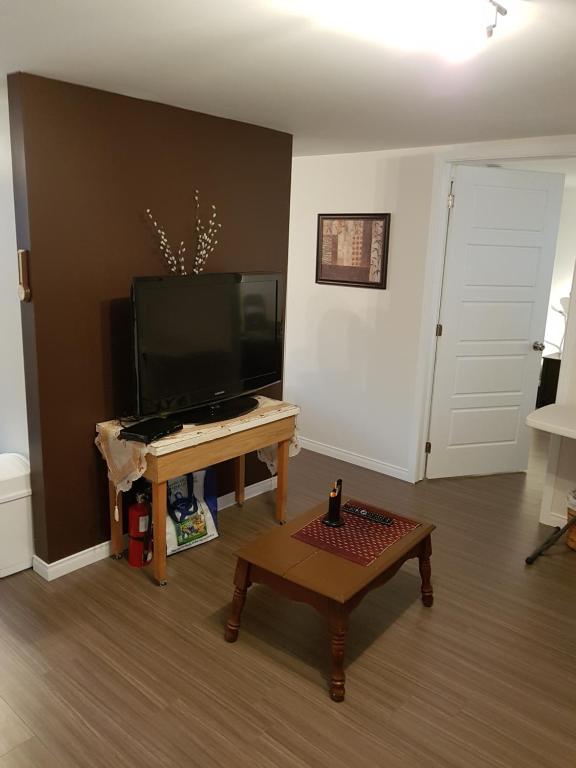 a living room with a flat screen tv and a coffee table at Gite La Ptite Falaise hébergement touristique in Sainte-Anne-des-Monts
